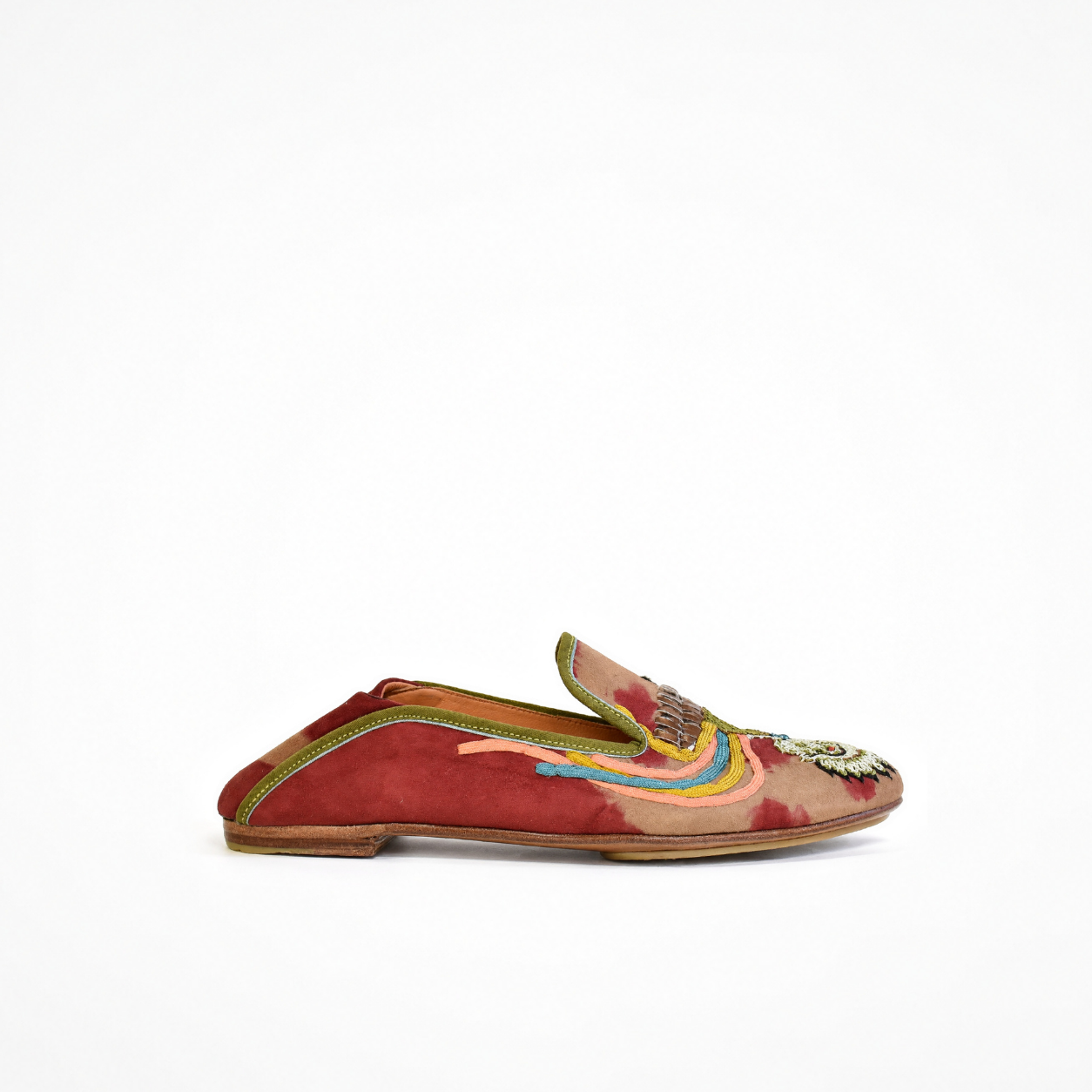 A single red suede loafer slip-on shoe with colorful embroidered details, rainbow stripes, and a silver-toned decorative embellishment on the toe, shown against a plain white background.