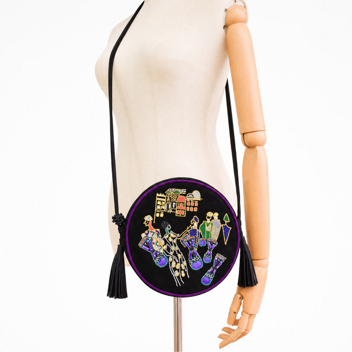 Mannequin wearing the black suede Marrakesh Round Bag as a crossbody bag with long strap and tassels