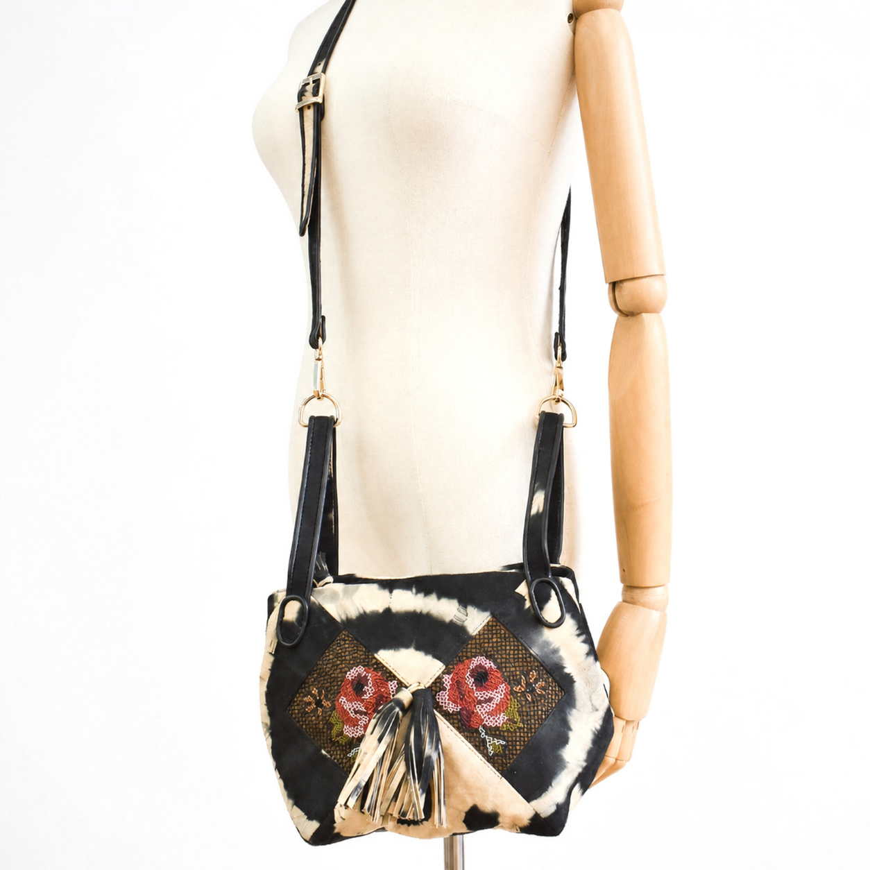 Mannequin wearing the black and beige tie-dye suede NORA BUNNY BAG with red floral embroidery