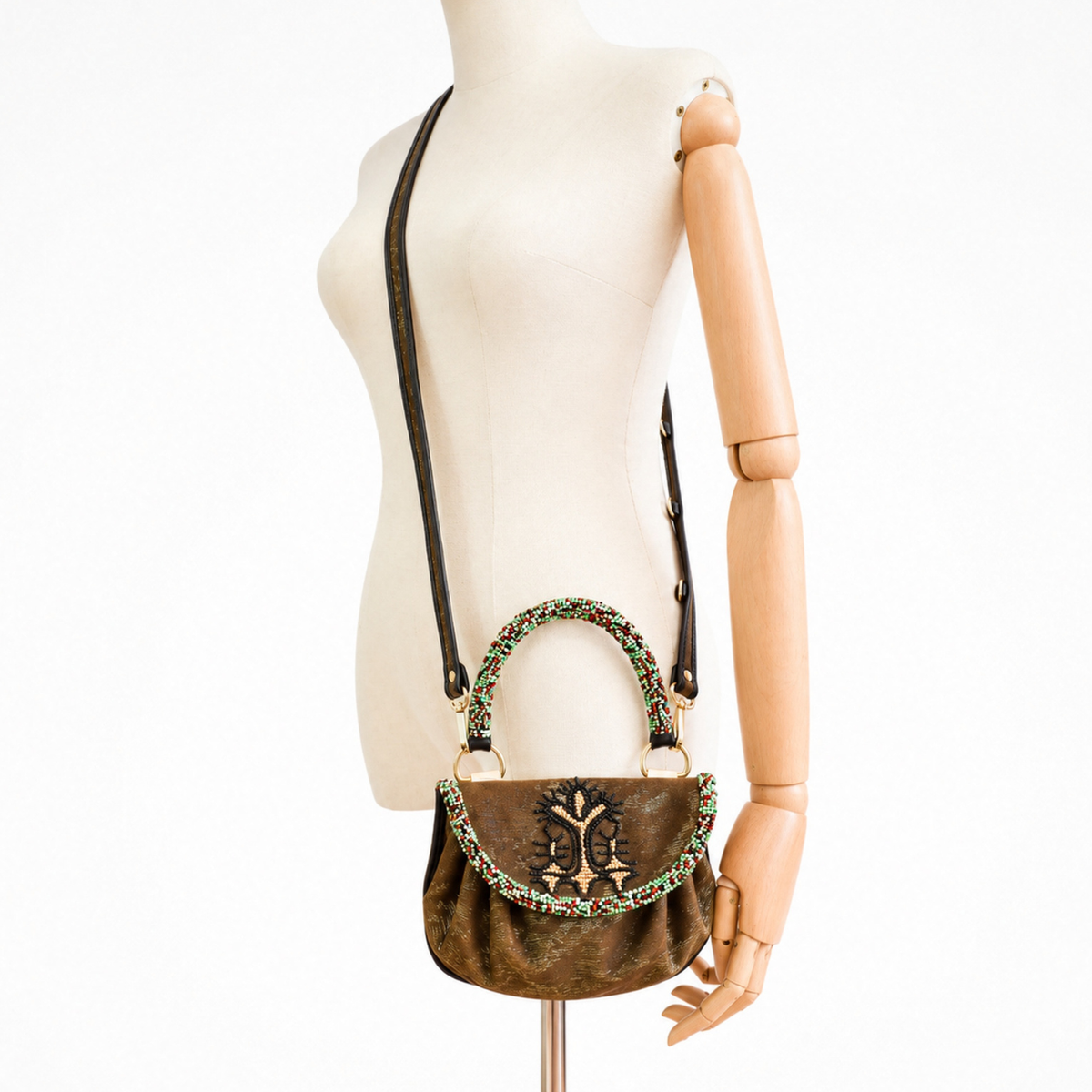 Mannequin wearing the metallic bronze-charcoal Sahara Accordion Handbag as a crossbody bag with beaded handle