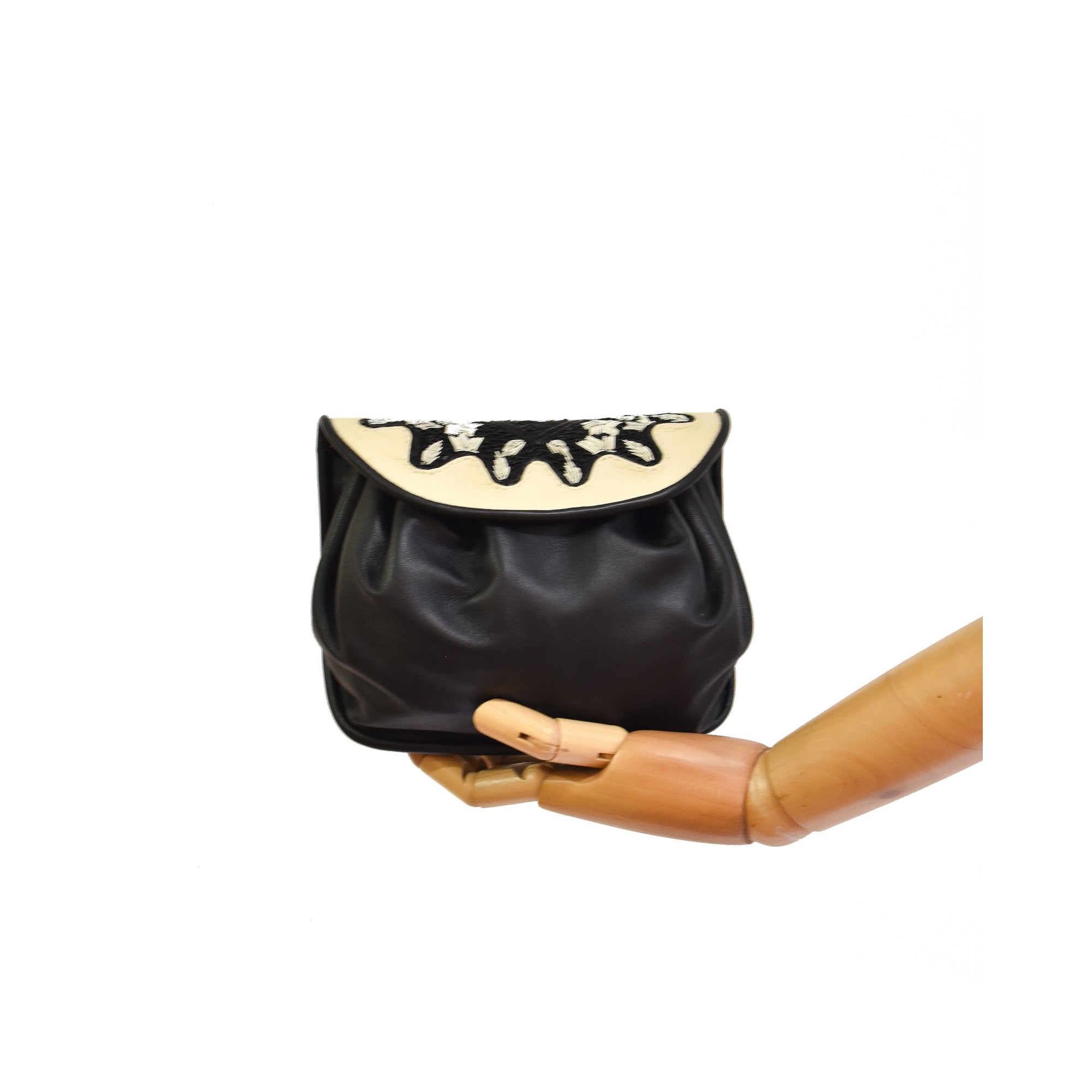 Compact black and white leather handbag with gathered base and gold clasps.