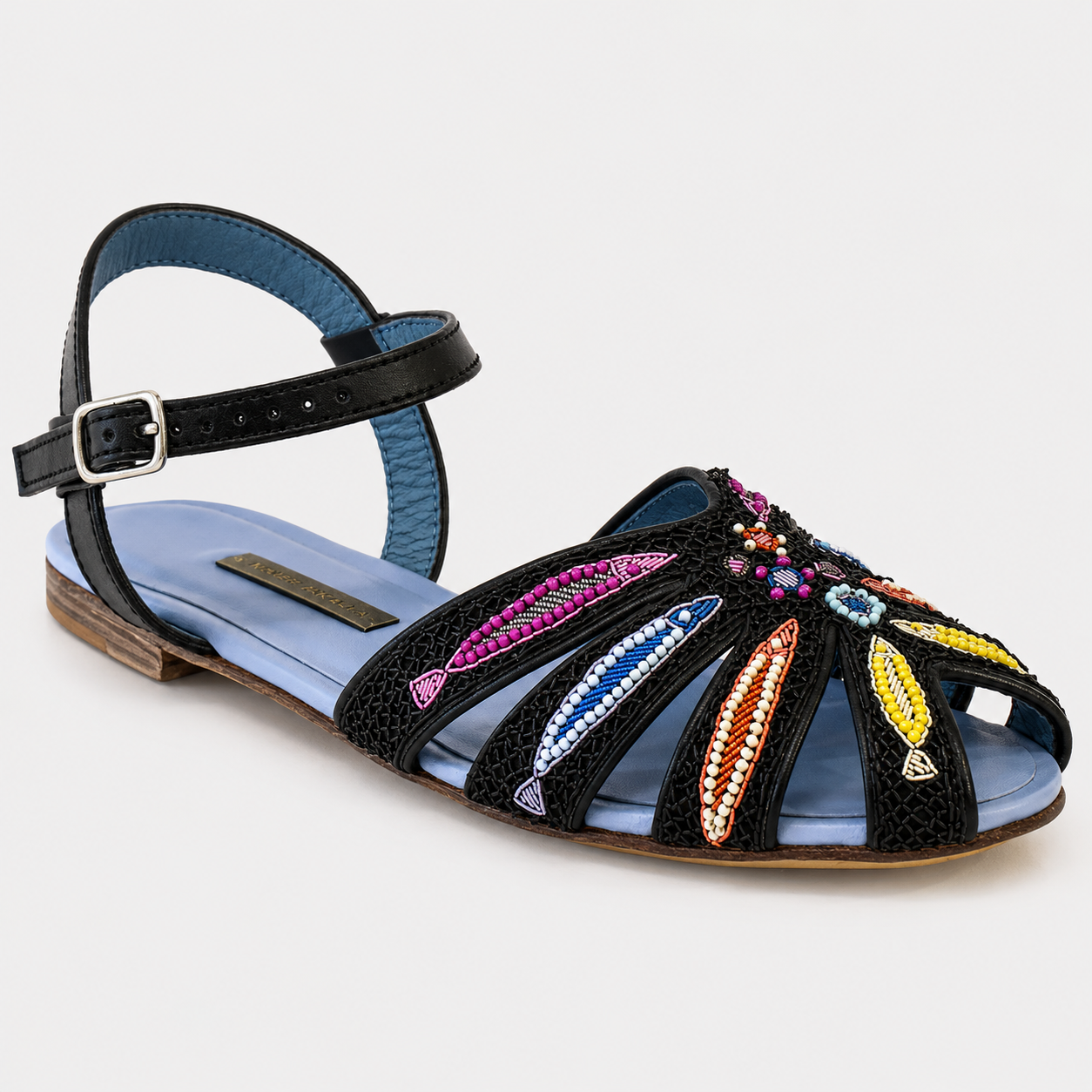 Black sandal with colorful embellishments on a light gray background