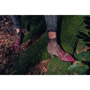 Burgundy embroidered suede ankle boots with tribal motifs worn outdoors