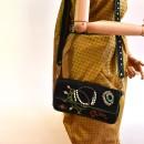 Meher KakaliaMeher Kakalia black Jewel Clutch worn crossbody, side view showing embroidered motifs.