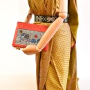 Meher KakaliaCoral elephant-embroidery pochette made from small leather stock, styled with a beige dress