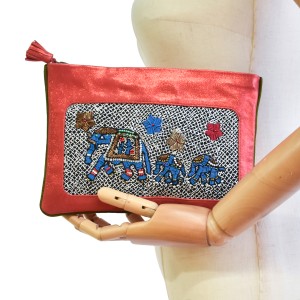Mannequin holding the limited-edition coral elephant-embroidered pochette