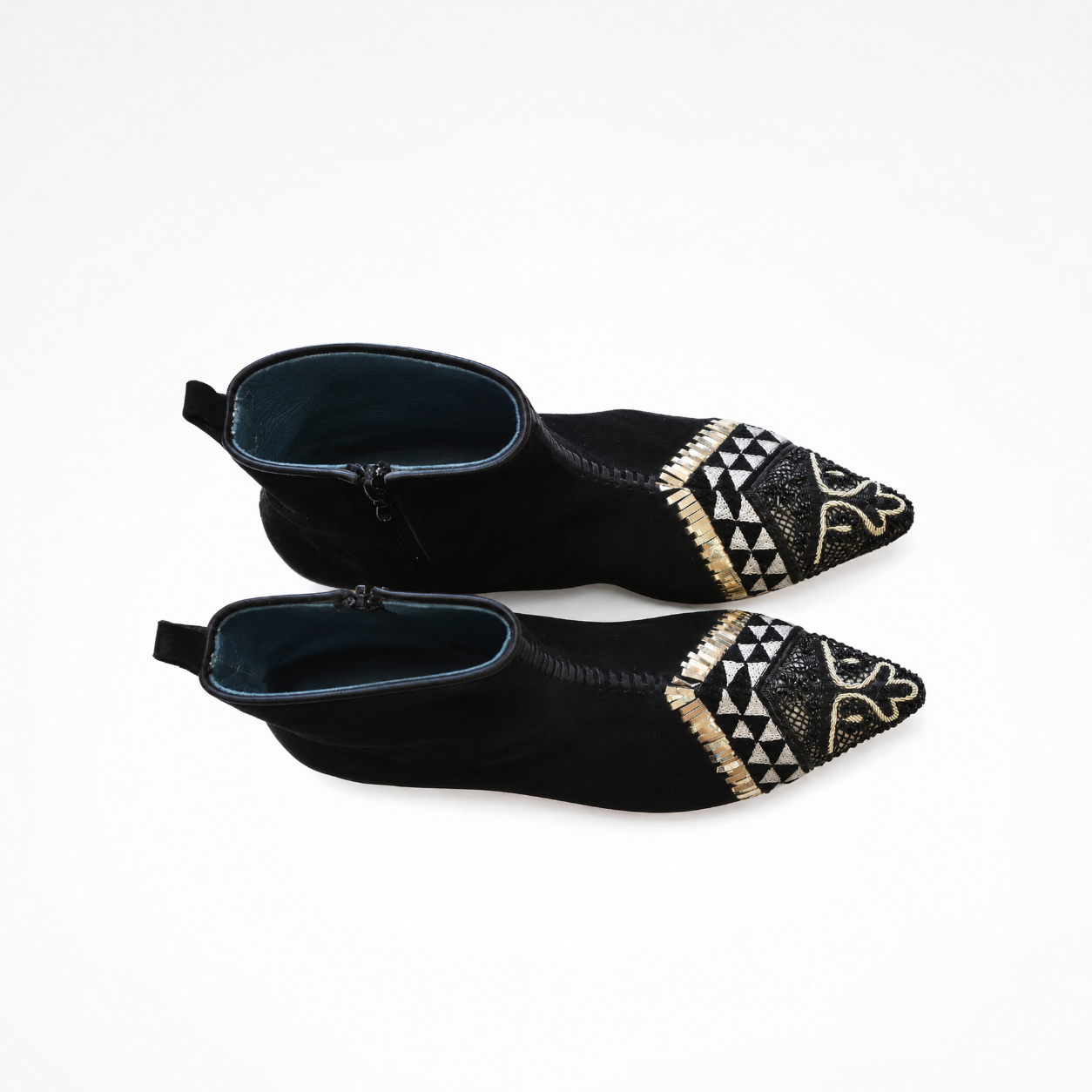 Pair of pointed black suede boots showing cream geometric embroidery and front stitching