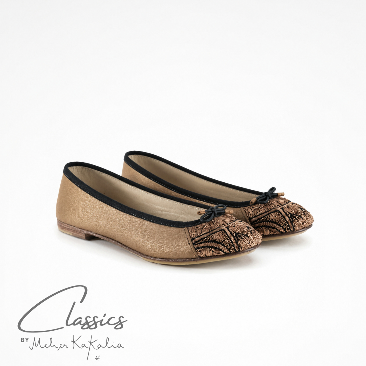 Pair of gold leather BIZI ballet flats with hand-embroidered toe caps, angled view