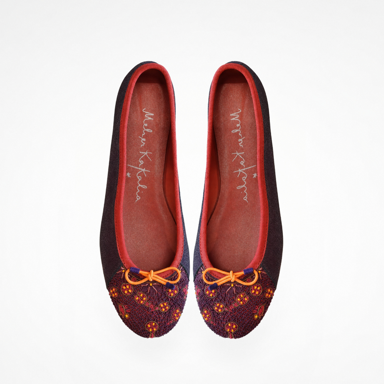 Pair of Eden Ballet flats in beige and black leather, top view showing embroidered toe panels and bows