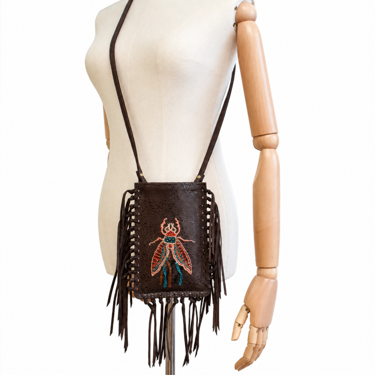Mannequin wearing the brown leather FRINGE Phone Bag crossbody with embroidered insect motif and leather fringe