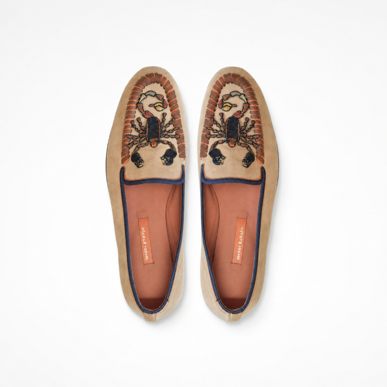 Pair of beige suede loafers showing scorpion embroidery and rounded toes