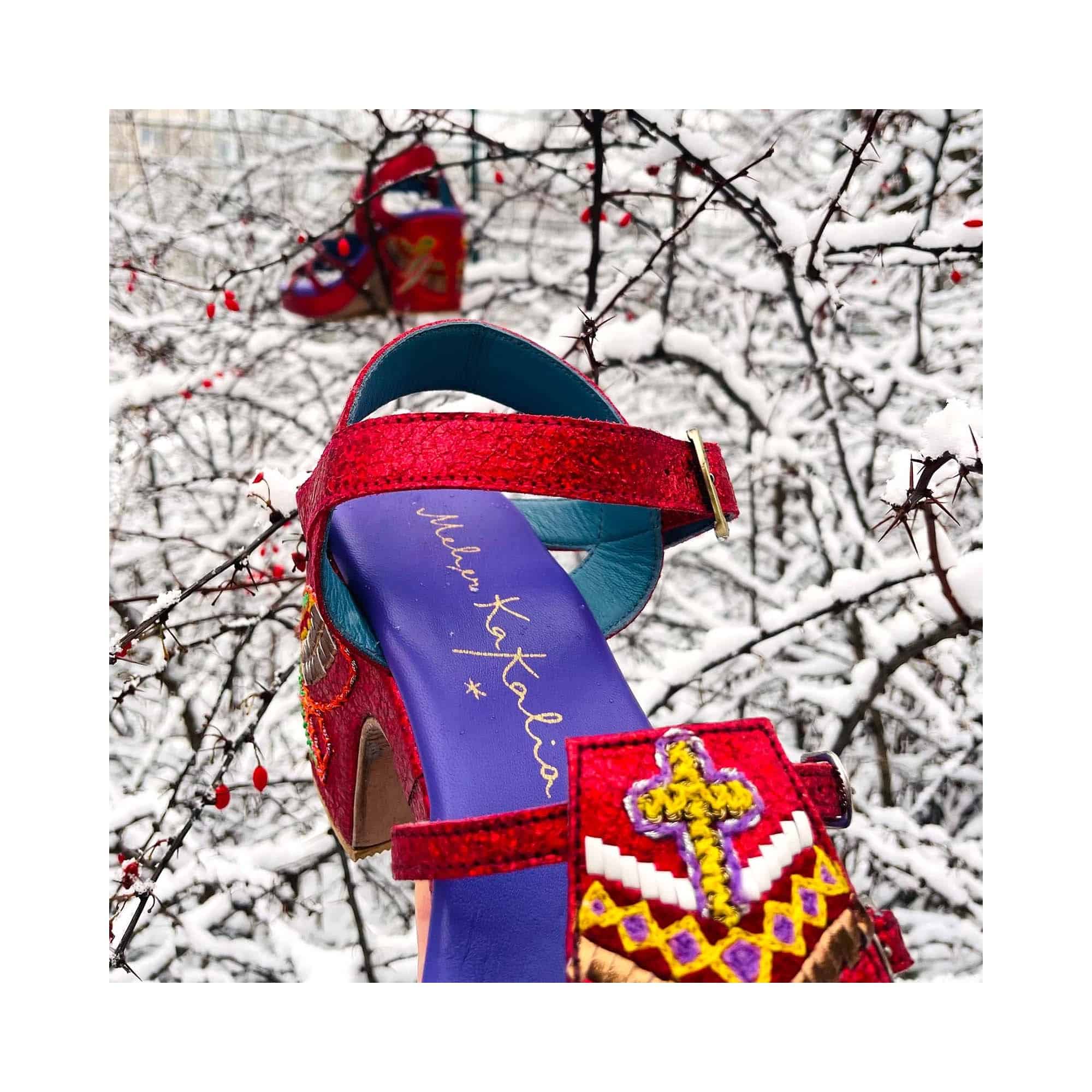GOLD HOPPER splash poppy – close-up of tribal embroidery and shimmering red leather against snowy branches