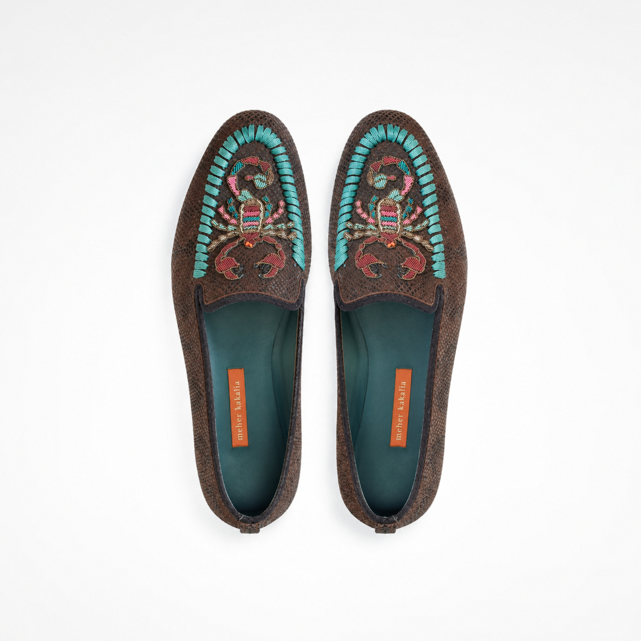 Pair of brown loafers showing turquoise and pink scorpion embroidery and rounded toes